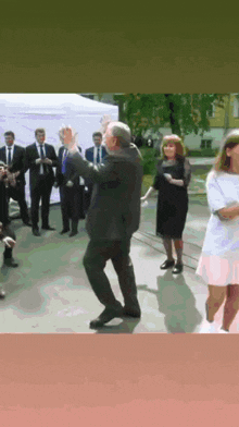 a man in a suit is dancing with a woman in a white dress