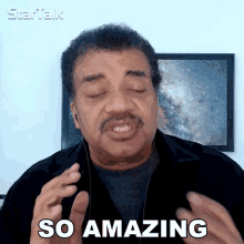 a man with headphones says so amazing in front of a framed picture