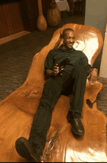 a man in a green shirt is sitting on a large wooden chair