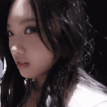 a woman with long black hair looks at the camera