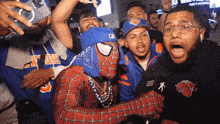a man in a spiderman costume is surrounded by fans wearing new york knicks shirts