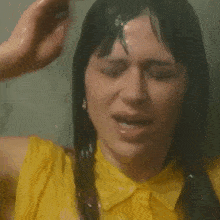a woman in a yellow shirt is washing her hair with her hand