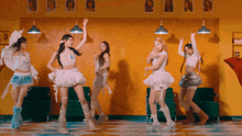 a group of girls are dancing in a room with pictures of women on the wall