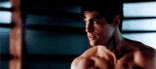 a shirtless man is standing in front of a punching bag in a dark room .