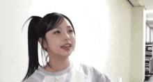 a young girl with a ponytail is standing in a hallway and smiling at the camera .