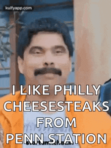a man with a mustache is saying that he likes philly cheesesteaks from penn station .