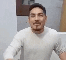 a man with a beard and mustache is wearing a white t-shirt .