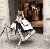 a woman is carrying a lot of shopping bags in front of a store