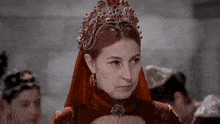 a woman in a red dress is wearing a tiara and earrings .