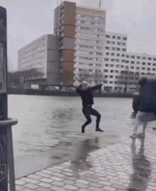 a man is jumping into a puddle of water in front of a building that says ' a ' on it