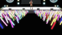 a girl is standing on a stage in front of a crowd with glowing sticks