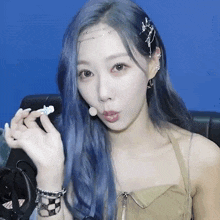 a woman with blue hair is wearing earrings and a bracelet