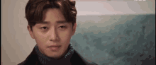a close up of a young man 's face wearing a turtleneck sweater and a black coat .
