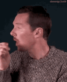 a man with a beard is wearing a sweater and making a face .