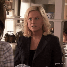 a woman in a black jacket is making a funny face while talking to another woman .