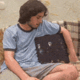 a man sits on a couch holding a picture that says thankyou on it