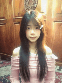 a girl with long black hair is wearing a pink top
