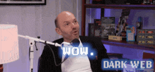 a man is sitting in front of a microphone with the words wow dark web behind him