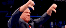 a man in a suit is giving a thumbs down sign .