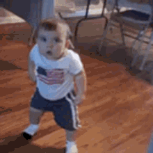 a baby is walking on a wooden floor .