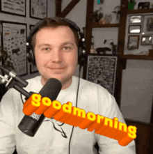 a man wearing headphones stands in front of a microphone and says " good morning "