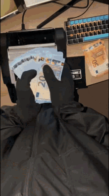 a person wearing black gloves is holding a bunch of 20 euro bills