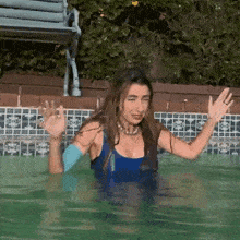 a woman in a blue bikini is swimming in a pool .