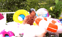 a man is playing in a pool of foam surrounded by inflatable balls