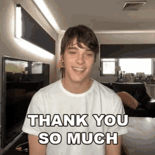 a young man is smiling and saying `` thank you so much '' while sitting in a living room .