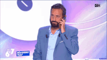 a man in a blue suit is talking on a cell phone in front of a screen that says le 67