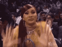 a woman is waving her hands in the air while sitting in a crowd of people .