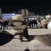 a group of people are walking down a street at night with russian writing on the bottom .