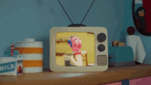 a cartoon character is sitting at a table on a television screen .