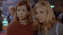 two women are standing next to each other in a crowded room