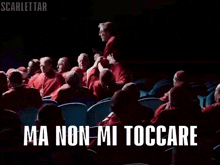 a group of people sitting in a dark auditorium with the words ma non mi toccareeeee written on the screen