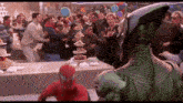 a man in a spiderman costume is standing in front of a crowd of people at a birthday party .