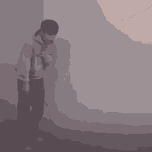 a man in a hoodie is standing in a room with smoke coming out of the window .