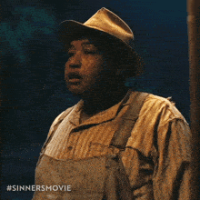 a man wearing overalls and a striped shirt has the hashtag #sinnersmovie on his chest