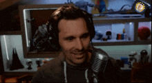 a man wearing headphones is smiling in front of a microphone in a room