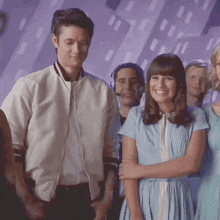 a man in a white jacket stands next to a woman in a light blue dress