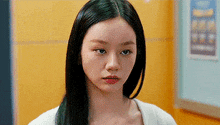 a woman with long black hair and green hair is standing in a hallway .