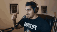a man wearing headphones and a shirt that says deadlift singing into a microphone