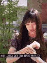 a woman with long hair and bangs is holding something in her hand and looking at her watch .