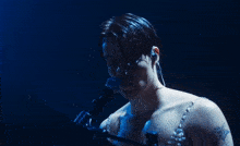 a man singing into a shure microphone with a tattoo on his chest