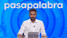 a man with his arms crossed in front of a blue background with the word pasapalabra