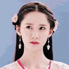 a close up of a woman 's face wearing earrings and a flower in her hair
