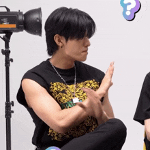 a man sitting in front of a camera with a question mark