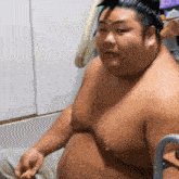 a shirtless man with a large belly is sitting in a room