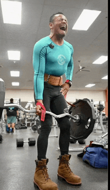 a man in a blue shirt is lifting a barbell in a gym with a tag that says ' usa '