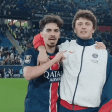 two soccer players are posing for a picture and one has a qatar airways jersey on